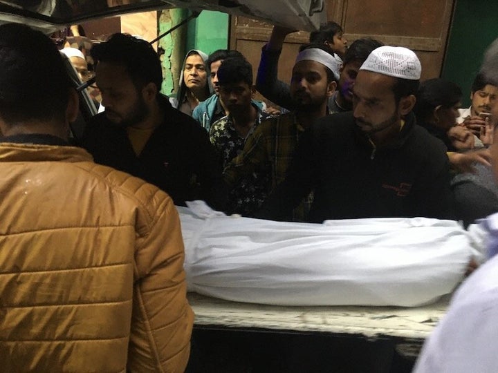 Faizan's family members receive his body at his home in Kardampuri on 29 February.