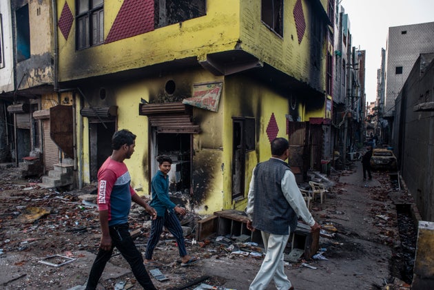 Men walk in front of damaged residential houses in a riot-affected area on March 1, 2020 in New