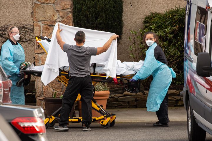 Healthcare workers transport a patient on a stretcher into an ambulance at Life Care Center of Kirkland on February 29, 2020 