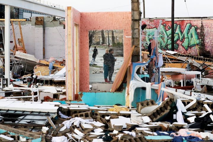 People are reflected in a mirror of a building destroyed by storms Tuesday in Nashville, Tenn.
