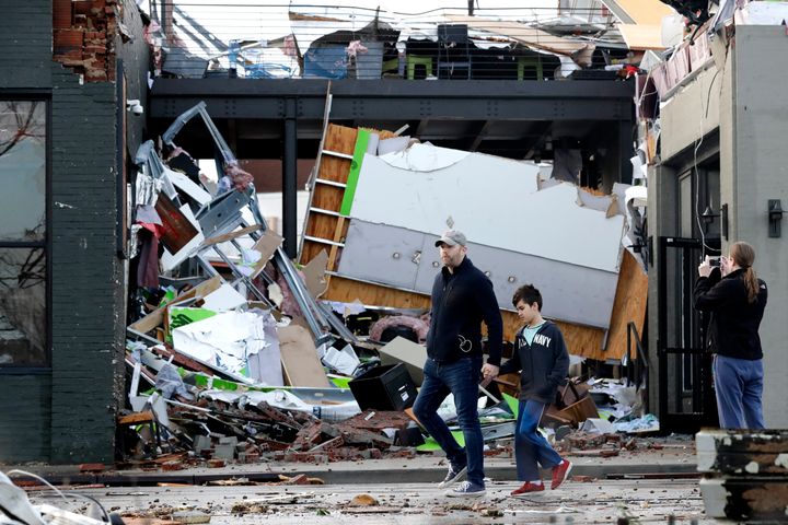 People walk past buildings damaged by storms in Nashville. At least eight people were killed and dozens of buildings destroyed.