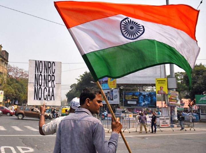A man holds a placard and a flag during a protest against the Citizenship Amendment Act (CAA), National Population Register (NPR) and the National Register of Citizens (NRC) in Kolkata on March 1, 2020. 