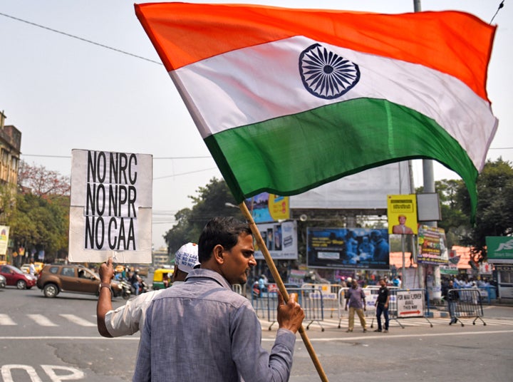 A man holds a placard and a flag during a protest against the Citizenship Amendment Act (CAA), National Population Register (NPR) and the National Register of Citizens (NRC) in Kolkata on March 1, 2020.