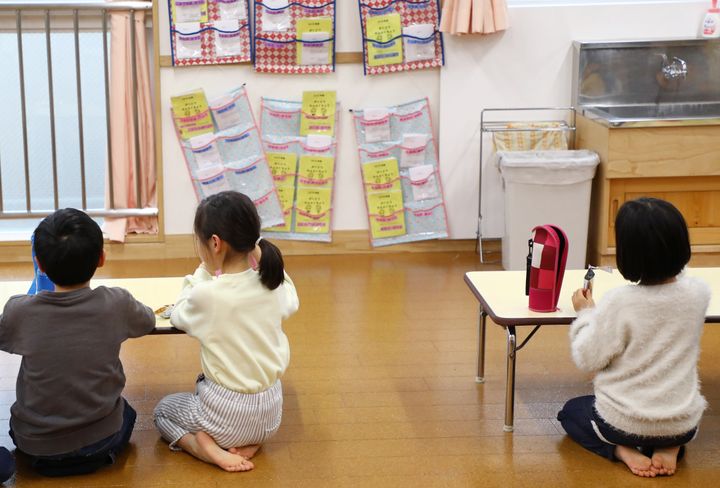 学童保育室での飛沫感染を防ぐため、テーブルの間隔を空け、壁に向かっておやつを食べる子どもたち＝3月2日、東京都足立区の千住あずま住区センター