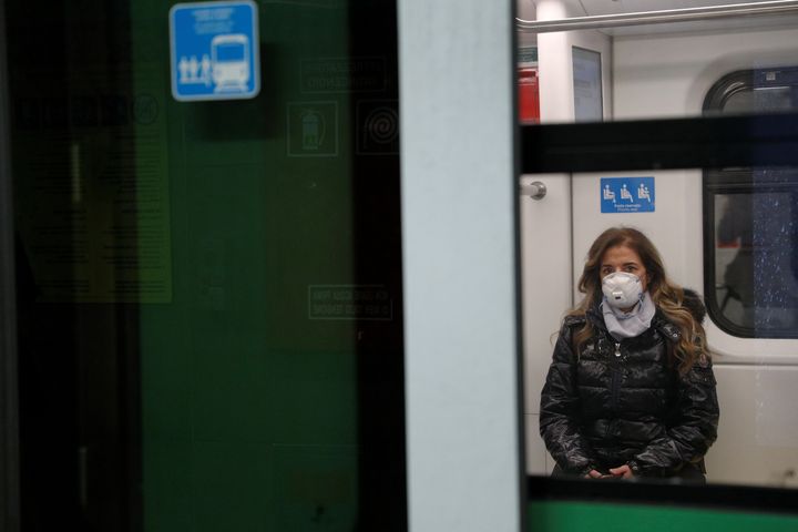 A woman wearing a protective face mask to prevent contracting the coronavirus sits inside a train at a subway station in Milan, Italy