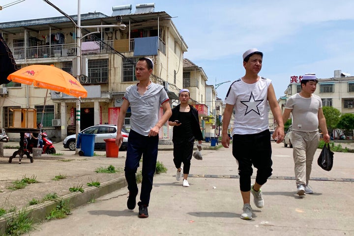 In this photo taken Wednesday, June 5, 2019, residents of the Hui Muslim ethnic minority walk in a neighborhood near an OFLIM factory in Nanchang in eastern China's Jiangxi province. 