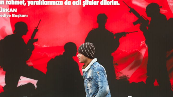 Μετανάστης στην Ανδριανούπολη μπροστά από μια αφίσα προς τιμήν των Τούρκων στρατιωτών που τραυματίστηκαν ή έπεσαν στο πεδίο της μάχης 5 Μαρτίου 2020 (AP Photo/Darko Bandic)