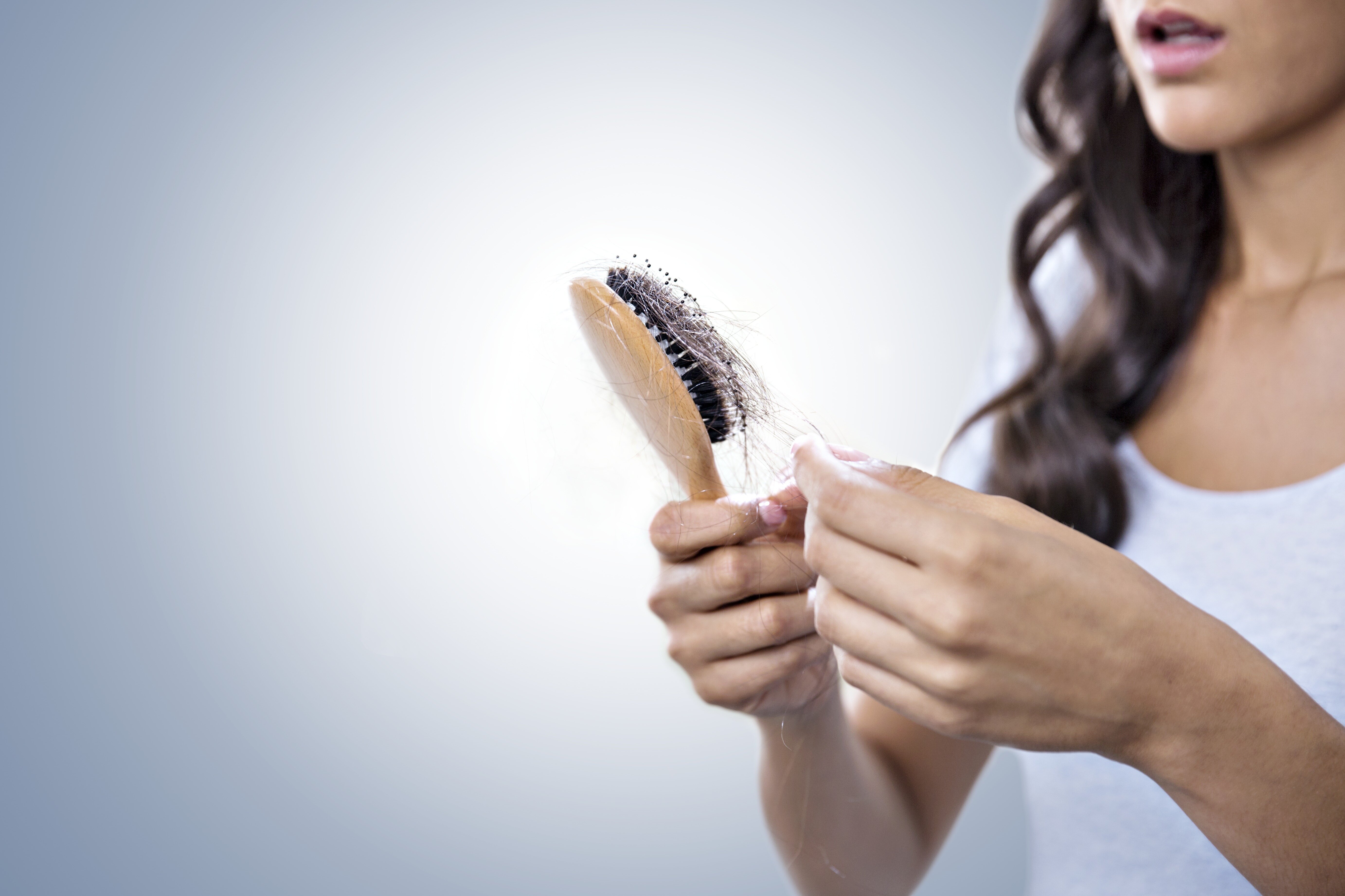 Premium Photo  Rear view young woman worried about hair loss problem  hormonal disbalance stress concept many hair fall after combing in hair  brush in hand female untangled her hair with a