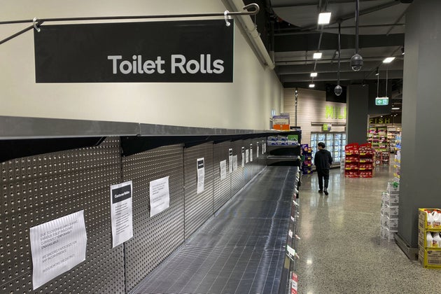 A shopper passes empty shelves usually stocked with toilet paper in a supermarket in Melbourne on March 5, 2020.