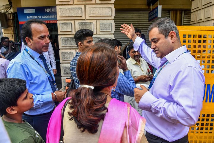 Yes Bank employees speak to customers gathered outside a branch in Mumbai on March 6, 2020.