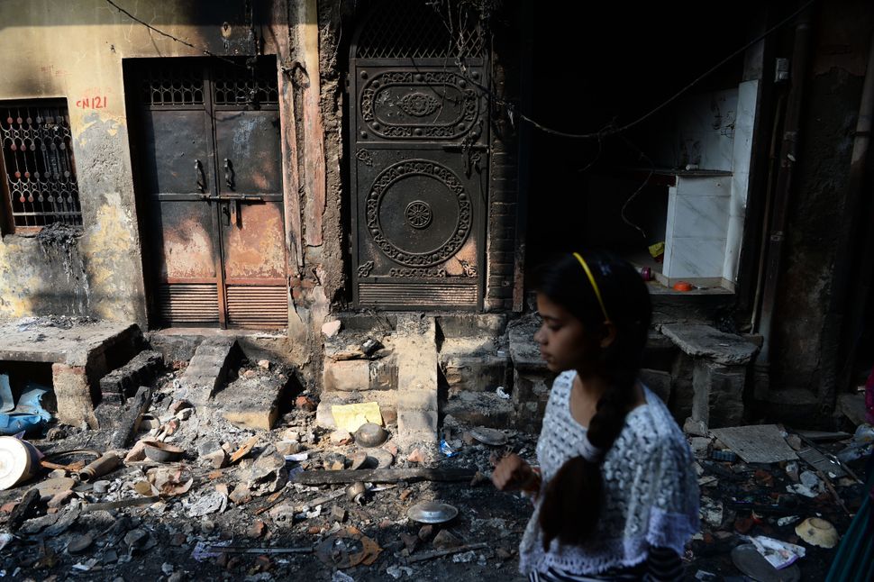 A resident walks past a burnt-out building on a residential area, in New Delhi on March 1, 2020.