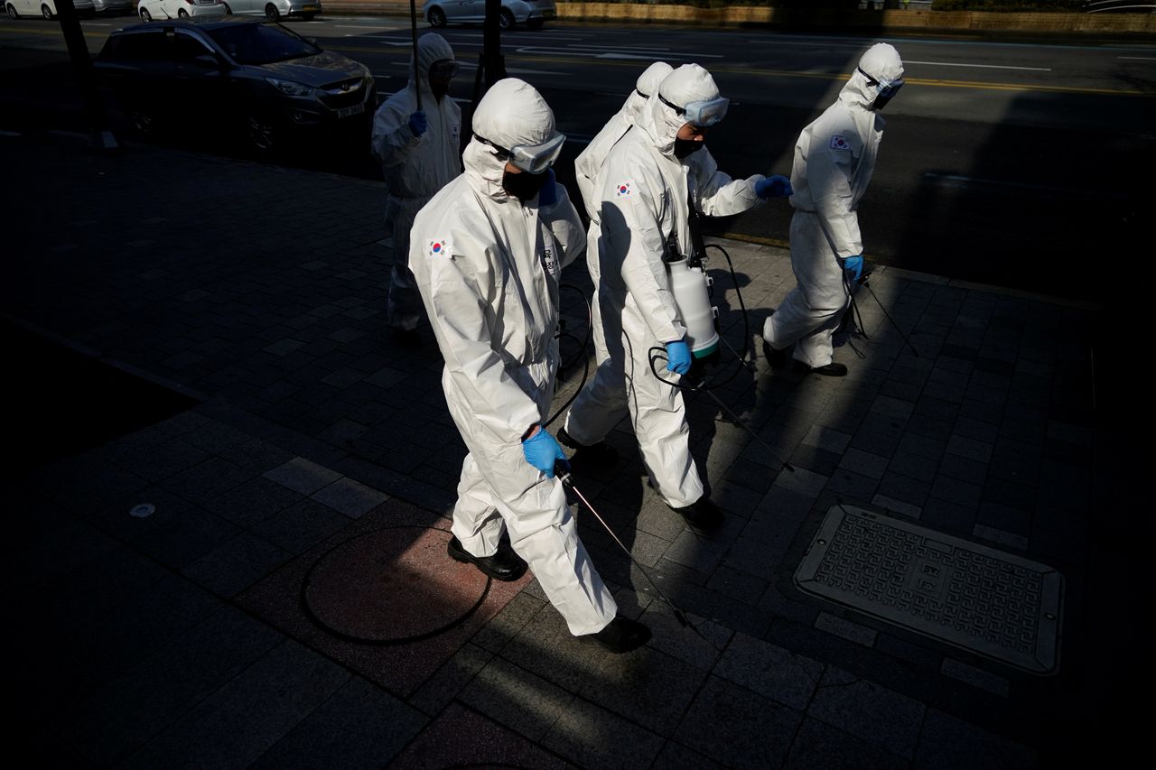 South Korean soldiers in protective gear sanitise a street at a shopping district in Seoul, South Korea. 