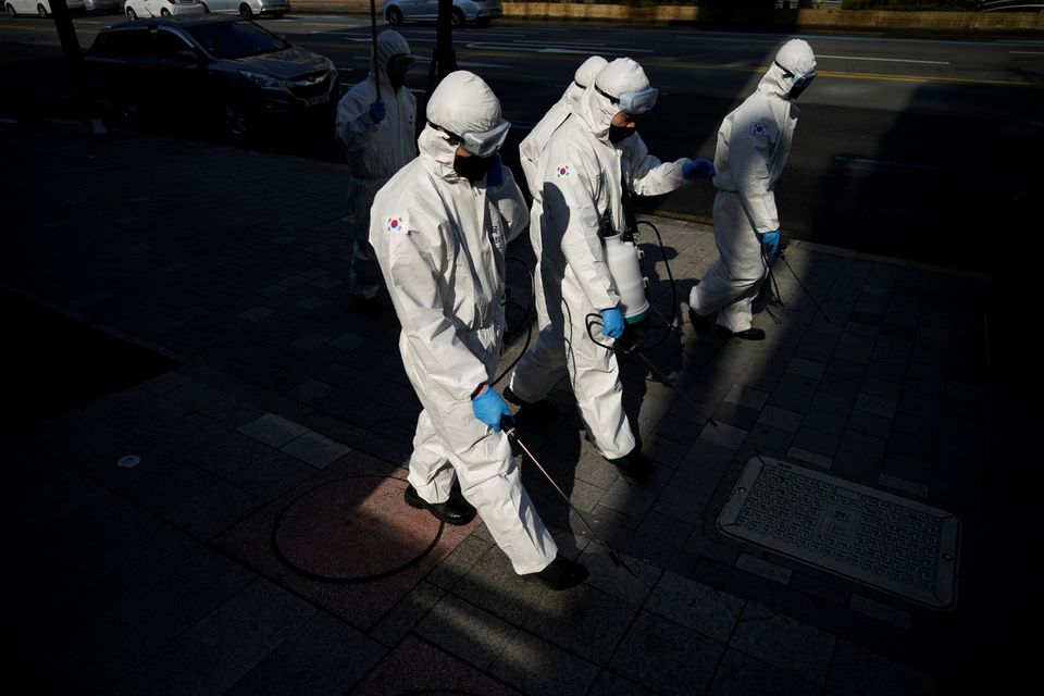 South Korean soldiers in protective gear sanitise a street at a shopping district in Seoul, South Korea. 