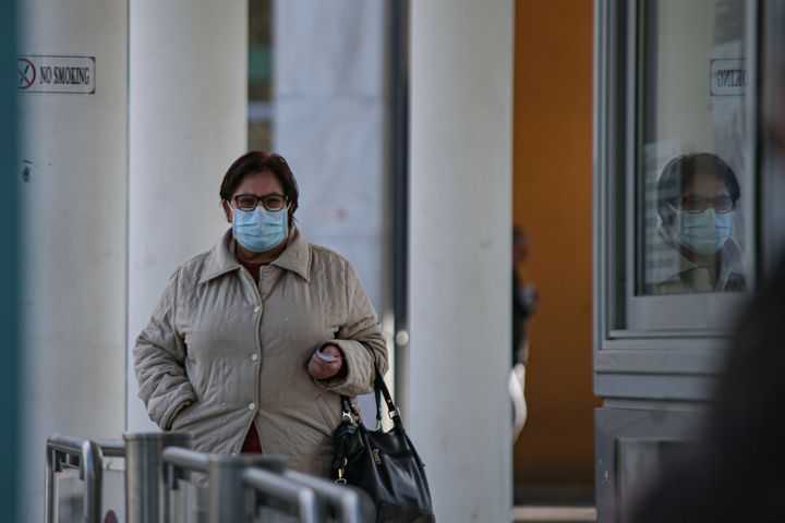A woman wearing a protective face mask walks outside of the Hospital that the first Coronavirus case was confirmed, in Thessaloniki, Greece 26 February 2020. (Photo by Achilleas Chiras/NurPhoto via Getty Images)