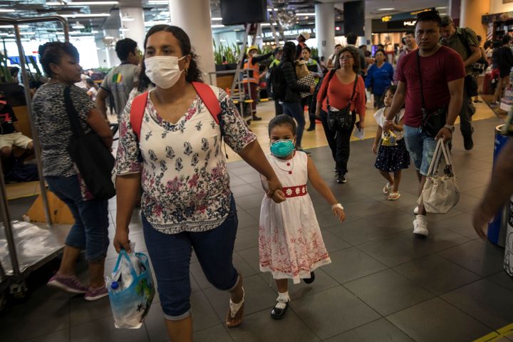 Wearing masks, passenger Gladys Ruiz Torres walks with her daughter Natali Oliva to the departure lounge at the international airport in Lima, Peru, Friday, March 6, 2020. Peruvian President Martin Vizcarra announced the first case of the new coronavirus in the country.
