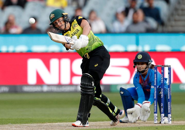 Australia's Alyssa Healy, left, drives the ball in front of IndiaÅfs Tanya Bhatia during the WomenÅfs T20 World Cup cricket final match against India in Melbourne, Sunday