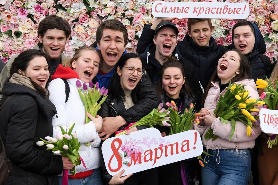 Participants react on the finish line of a 400m running event held on the International Women's day in Moscow, during which hundreds of me run with a tulip and gift it to women on the finishing line.  