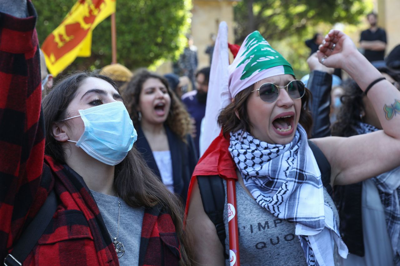 Lebanese women, including one wearing a protective mask due to coronavirus, gesture during a march in Beirut.