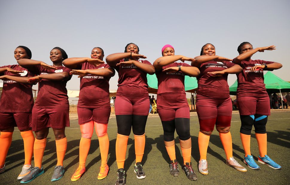 Women line up with their hands arranged as equality signs during a friendly football match in Abuja, Nigeria. 