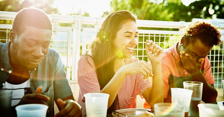 Woman laughing while dining with friends.