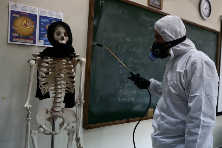 Υπάλληλος απολυμαίνει σχολική αίθουσα σε γυμνάσιο της Αθήνας (Photo by Panayotis Tzamaros/NurPhoto via Getty Images)