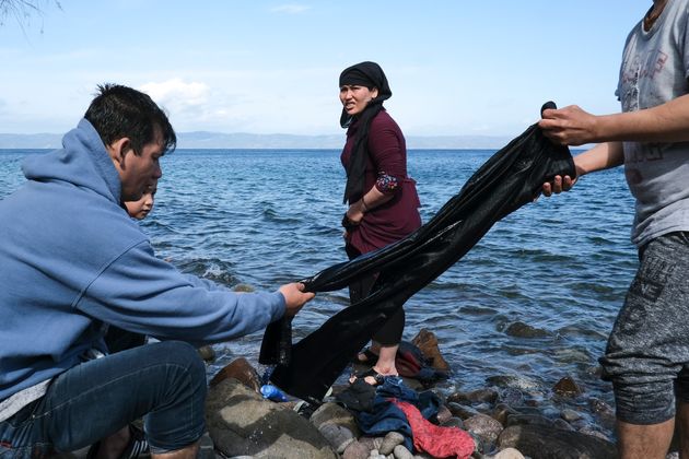 Migrants who arrived recently from Turkey wash clothing in the sea at the village of Skala Sikaminias,...