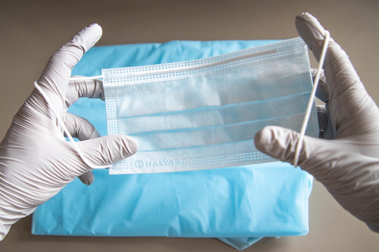 A health care worker holds a surgery mask