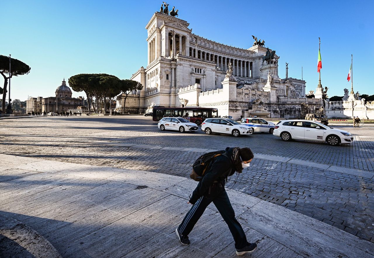Με μάσκα και βήμα γοργό μια γυναίκα περπατά στο κέντρο της Ρώμης. 