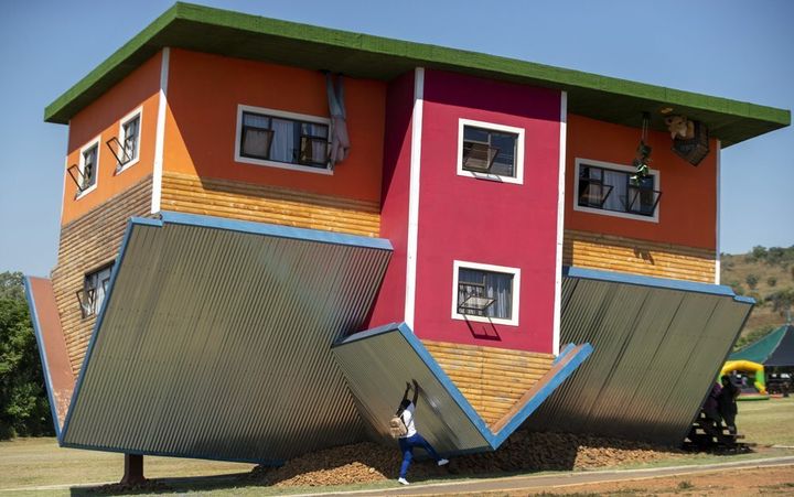 A visitor pretends to hold the structure up at the upside-down house in Hartbeespoort, South Africa. 