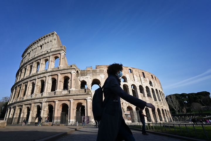 A tourist wearing a respiratory mask walks past the closed Colisseum monument in Rome.