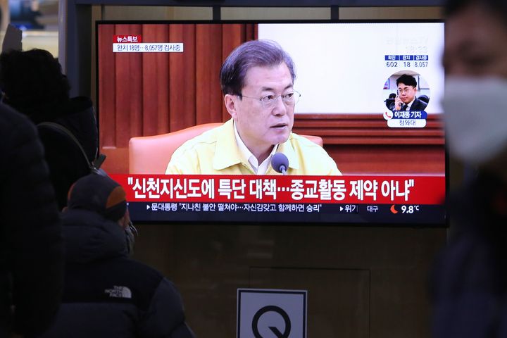 People watch a TV screen showing South Korean President Moon Jae-in's speech during a news program at the Seoul Railway Station in Seoul, South Korea, Sunday, Feb. 23, 2020. Moon has put his country on its highest alert for infectious diseases, saying Sunday that officials should take "unprecedented, powerful" steps to fight a viral outbreak. The signs read "Measures for Shincheonji believers." (AP Photo/Ahn Young-joon)