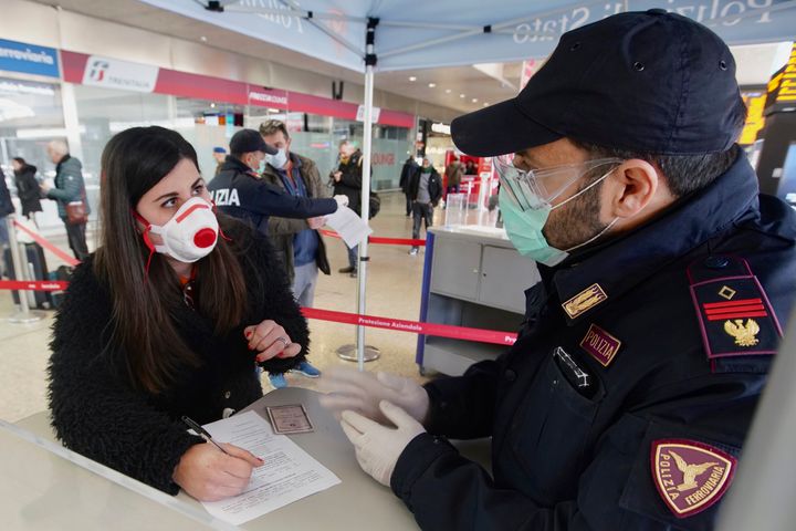 A traveler wears a mask as she fills out a form at a check point set up by border police inside Rome's Termini train station, Tuesday, March 10, 2020. In Italy the government extended a coronavirus containment order previously limited to the country’s north to the rest of the country beginning Tuesday, with soldiers and police enforcing bans. (AP Photo/Andrew Medichini)