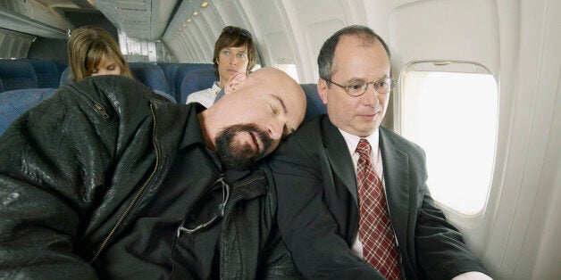 Man Sleeping on a Plane With His Head Resting on a Businessman's Shoulder