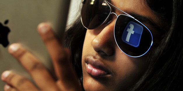 The 'Facebook' logo is reflected in a young Indian woman's sunglasses as she browses on a tablet in Bangalore on May 15, 2012. World's popular and leading social networking company Facebook Inc., founded in a Harvard dorm room by Mark Zuckerberg whose current value exceeds 100 billion USD, will be making an initial public offering (IPO) which is slated to be Silicon Valley's biggest-ever. AFP PHOTO/Manjunath KIRAN (Photo credit should read Manjunath Kiran/AFP/GettyImages)