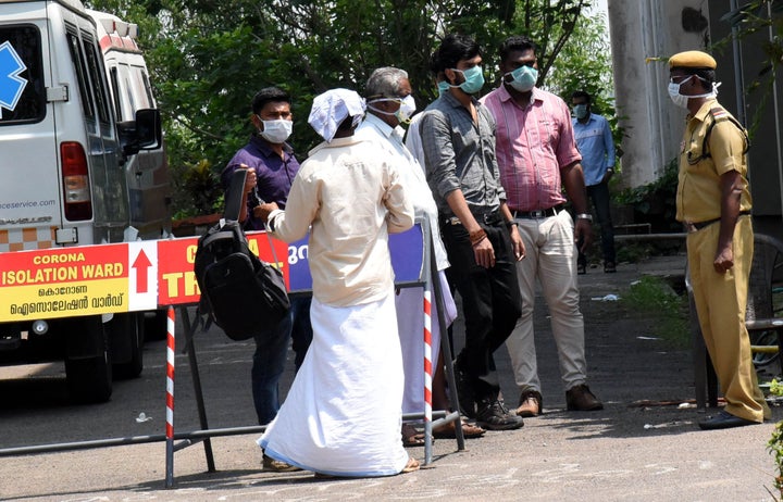 People are seen wearing masks outside the special isolation ward set up to provide treatment to novel coronavirus patients at Ernakulam Medical college, in Kerala, March 9, 2020.