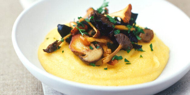 Dish of soft polenta topped with sauteed wild mushrooms garnished with parsley