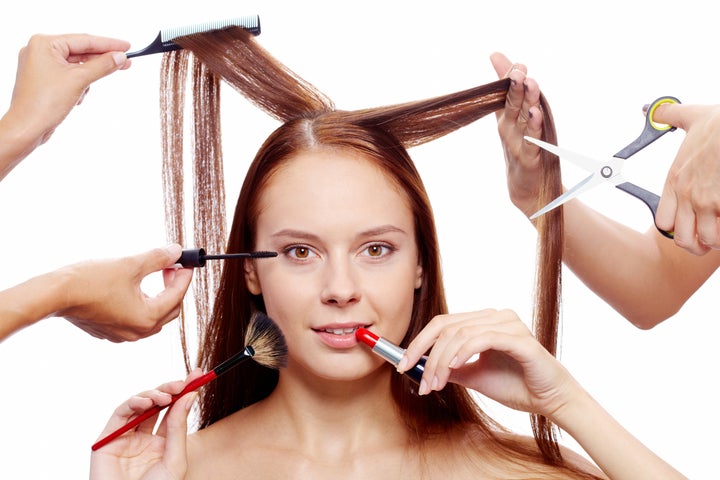 Portrait of young female surrounded by hands with beauty tools looking at camera