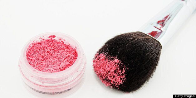 A make-up or cosmetic brush and pink mineral powder blush.