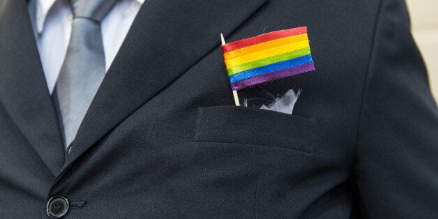 The father of a bride wears a rainbow flag during the wedding ceremony at the Court of Justice of the State of Rio de Janeiro in Rio de Janeiro, Brazil, on December 8, 2013. 130 gay couples are getting married in the first massive wedding ceremony since the first gay marriage in Rio de Janeiro in 2011. AFP PHOTO / YASUYOSHI CHIBA (Photo credit should read YASUYOSHI CHIBA/AFP/Getty Images)