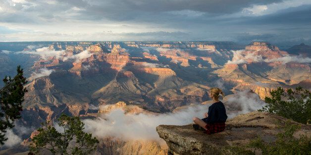UNITED STATES - 2015/08/07: A young woman is sitting on a rock near Yavapai Point on the South Rim overlooking the Grand Canyon with clearing clouds after a thunderstorm in the Grand Canyon National Park in northern Arizona, USA. (Photo by Wolfgang Kaehler/LightRocket via Getty Images)