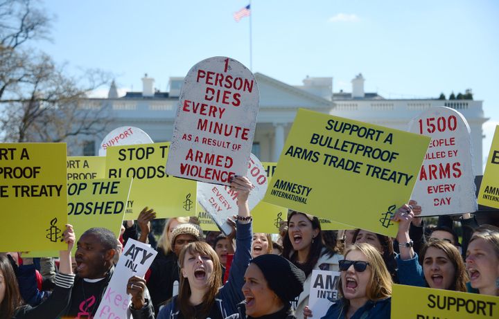 Demonstrators from Amnesty International chant outside the White House in Washington, DC, March 22, 2013, as they protest calling for strong support for a comprehensive global Arms Trade Treaty (ATT). AFP PHOTO/Jim WATSON (Photo credit should read JIM WATSON/AFP/Getty Images)