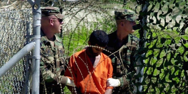 Guantanamo Bay, CUBA: (FILES) This 02 March, 2002, file photo shows a detainee escorted by two US Army MPs at Camp X-Ray in Guantanamo Bay, Cuba. The detainee was being lead to the Joint Interrogation Facility to be interviewed by government investigators. The Organization for Security and Cooperation in Europe (OSCE) in a report released 01 July, 2005, said the US should close the Guantanamo Bay detention camp because it is ineffective in fighting terrorism and fuels anti-US anger worldwide. The 14-page report, drawn up for OSCE's parliamentary assembly, said the camp could drive 'a generation of young Muslims' into Al-Qaeda and other such groups. 'We recommend terminating the Guantanamo detention facility, by announcing a calendar of closure,' said the report, drawn up by Belgian senate president Anne-Marie Lizin, who is rapporteur for the OSCE body. AFP PHOTO/Peter MUHLY/FILES (Photo credit should read PETER MUHLY/AFP/Getty Images)