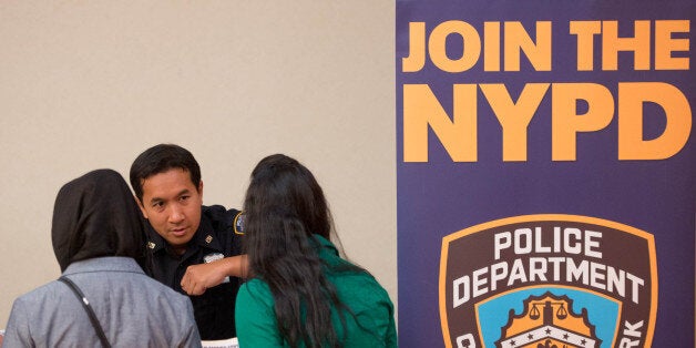 Kim Thy of the New York City Police Department (NYPD), center, speaks with job seekers at Choice Career Fairs' New York career fair at the Holiday Inn Midtown in New York, U.S., on Tuesday, May 13, 2014. The U.S. Department of Labor is scheduled to release initial and continuing jobless claims data on May 15. Photographer: Craig Warga/Bloomberg via Getty Images