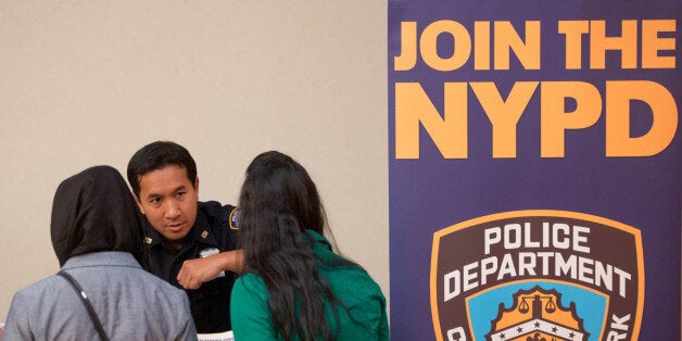 Kim Thy of the New York City Police Department (NYPD), center, speaks with job seekers at Choice Career Fairs' New York career fair at the Holiday Inn Midtown in New York, U.S., on Tuesday, May 13, 2014. The U.S. Department of Labor is scheduled to release initial and continuing jobless claims data on May 15. Photographer: Craig Warga/Bloomberg via Getty Images 