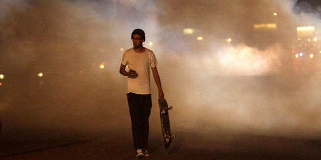 FERGUSON, MO - AUGUST 17 : A man with a skateboard protesting Michael Brown's murder walks away from tear gas released by police August 17, 2014 in Ferguson, Missouri. Despite the Brown family's continued call for peaceful demonstrations, violent protests have erupted nearly every night in Ferguson since his death.. (Photo by Joshua Lott/Getty Images)