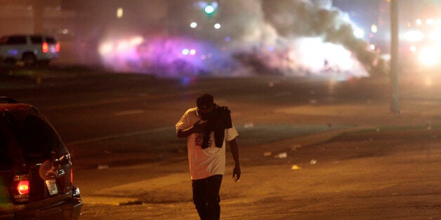 FERGUSON, MO - AUGUST 17 : A man protesting Michael Brown's murder walks away from tear gas released by police August 17, 2014 in Ferguson, Missouri. Despite the Brown family's continued call for peaceful demonstrations, violent protests have erupted nearly every night in Ferguson since his death. (Photo by Joshua Lott/Getty Images)