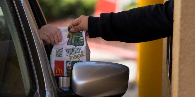 A customer receives an order from an employee at the drive-thru of a McDonald's Corp. restaurant in San Pablo, California, U.S., on Wednesday, Jan. 22, 2014. McDonald's Corp., the world's largest restaurant chain, posted fourth-quarter profit that was little changed from a year earlier as U.S. same-store sales fell amid shaky consumer confidence and increased competition. Photographer: David Paul Morris/Bloomberg via Getty Images