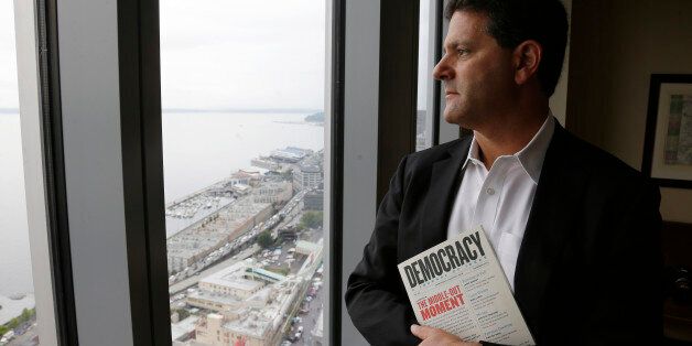 FILE - In this Aug. 2, 2013 file photo, venture capitalist Nick Hanauer stands by the window of his office in downtown Seattle. He holds a copy of "Democracy: A Journal of Ideas," which includes an article he co-authored promoting an economy driven by a strong middle class. (AP Photo/Ted S. Warren, File)