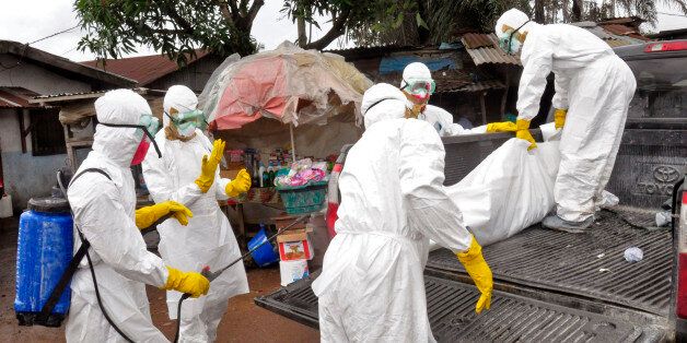 Health workers carry load the body of a woman that they suspect died from the Ebola virus, onto a truck in front of a makeshift shop in an area known as Clara Town in Monrovia, Liberia, Wednesday, Sept. 10, 2014. A surge in Ebola infections in Liberia is driving a spiraling outbreak in West Africa that is increasingly putting health workers at risk as they struggle to treat an overwhelming number of patients. A higher proportion of health workers has been infected in this outbreak than in any previous one. (AP Photo/Abbas Dulleh)