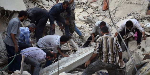 DAMASCUS, SYRIA - SEPTEMBER 24: Syrian men search for survivors in the rubble of a collapsed building following the Syrian army's airstrikes on the opposition controlled Duma district, in the suburbs of Damascus, Syria on September 24, 2014. (Photo by Yousef Albostany/Anadolu Agency/Getty Images)